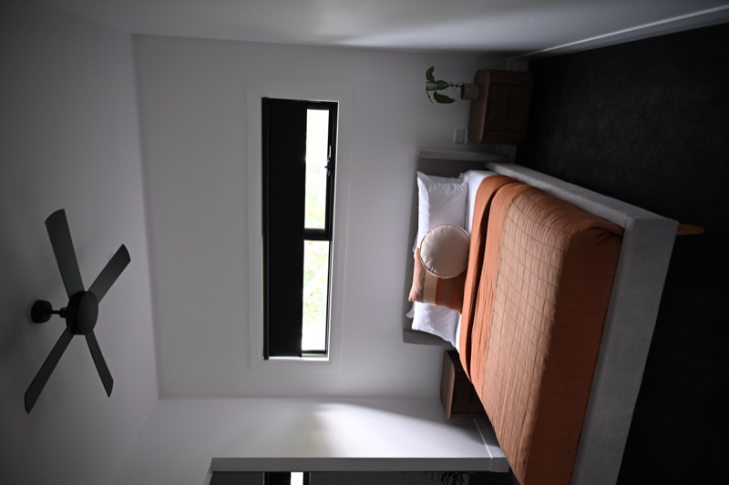 Black blockout roller blind fitted to a highlight window above a bed in a contemporary bedroom